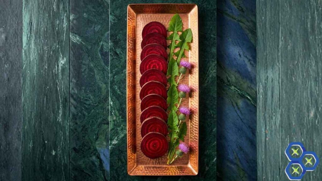 Flat lay of raw beet root, dandelion leaves, and thistle heads on a copper tray.